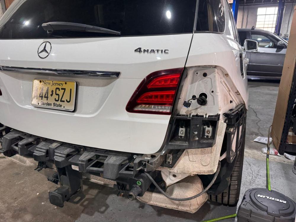 White Mercedes-Benz GLE with the rear bumper off for repair